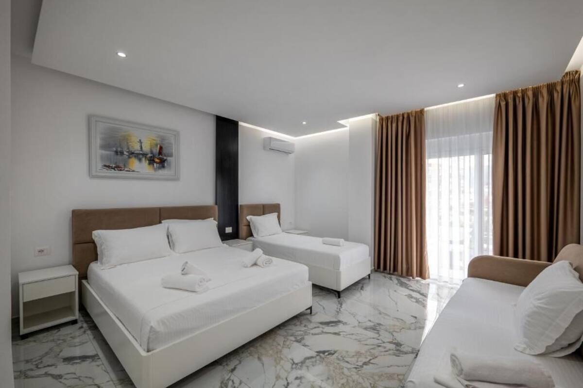 Une chambre d’hôtel avec deux lits, un canapé, une table de chevet et un tableau au mur.