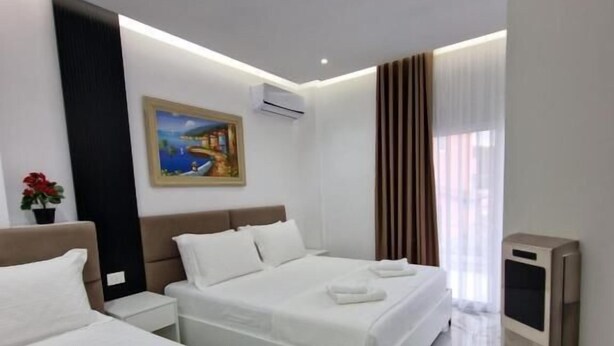 Hotelkamer met twee bedden, een schilderij aan de muur, een airconditioning, een televisie en een marmeren vloer.