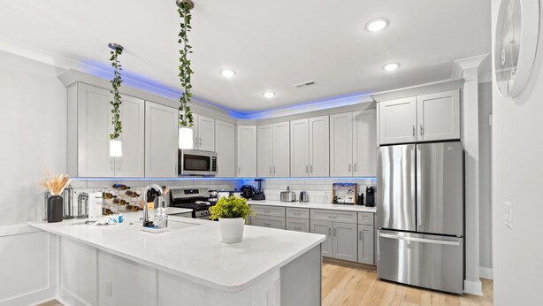 A modern kitchen with white cabinetry, stainless steel appliances, and a central island.
