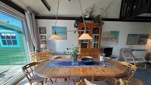 A dining area with a wooden table, chairs, and hanging lamps. - Pet-free vacation home on the North Sea (Ellemeet)