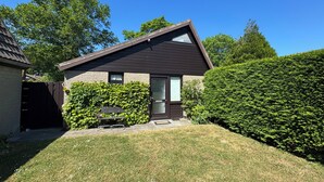 A house with a sloped roof, a front door, and a small front yard with a bench and a hedge. - Pet-free vacation home on the North Sea (Ellemeet)