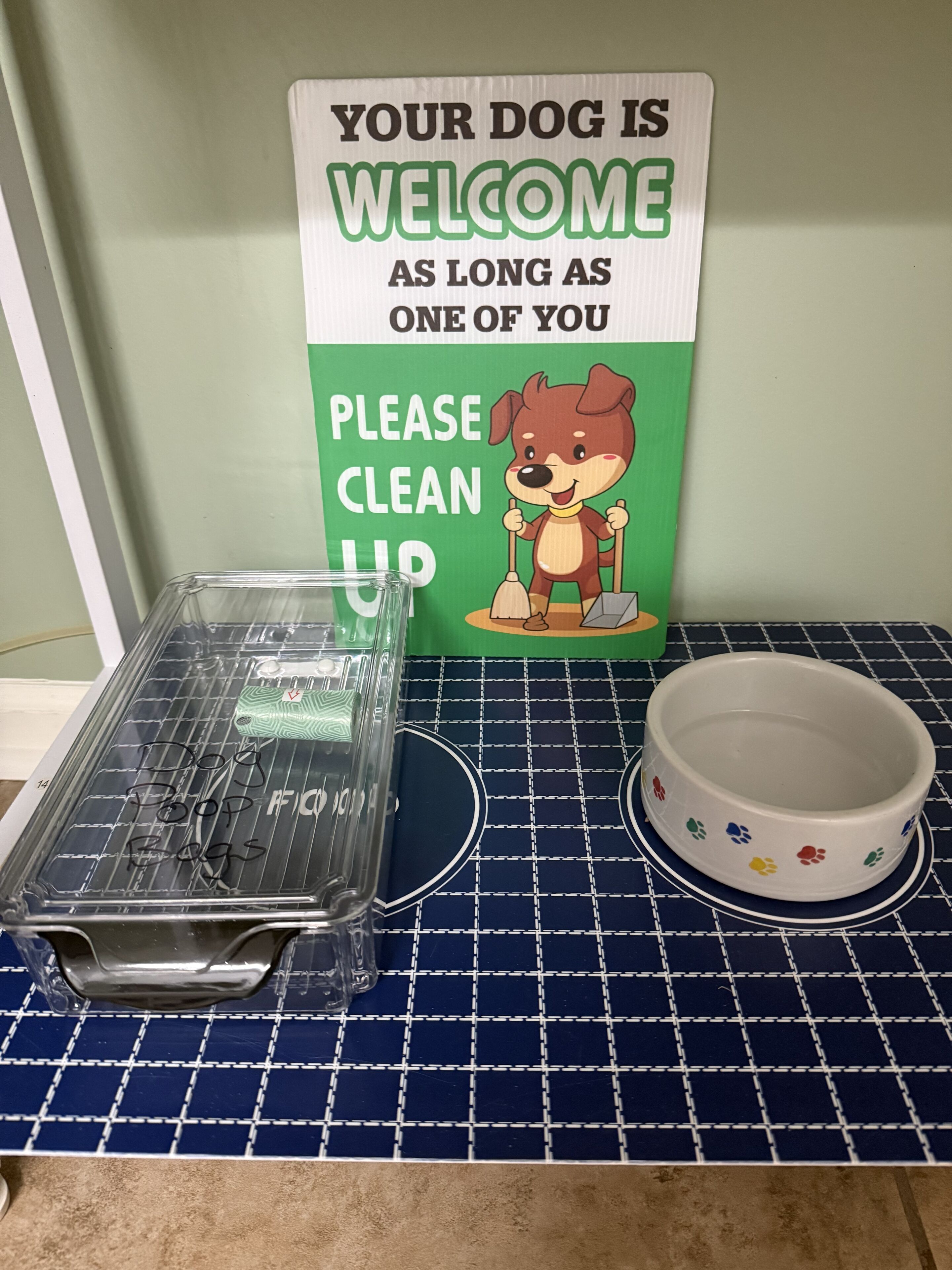 A pet-friendly sign in a room with a tiled floor and a pet bowl.