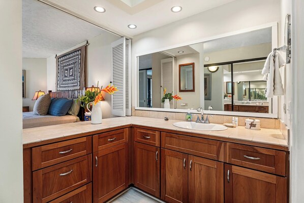 A modern bathroom with a large mirror, wooden cabinets, and a sink.