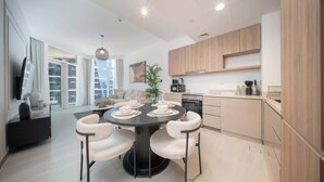 Une cuisine moderne avec des meubles de couleur bois clair, un îlot central doté de chaises et une table à manger pour quatre personnes.