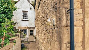 Traditional stone building with a single window and wooden door, set amidst a charming alleyway.