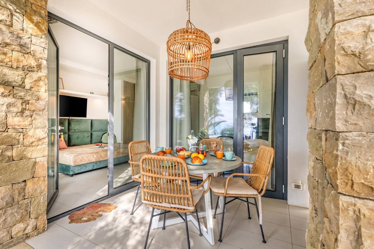 Un coin repas avec des chaises en osier, une table ronde et un luminaire suspendu.