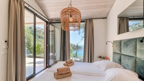 A modern hotel room with a large bed, a view of the sea, and a wooden ceiling. - Holiday Resort Balzi Rossi (Ventimiglia)