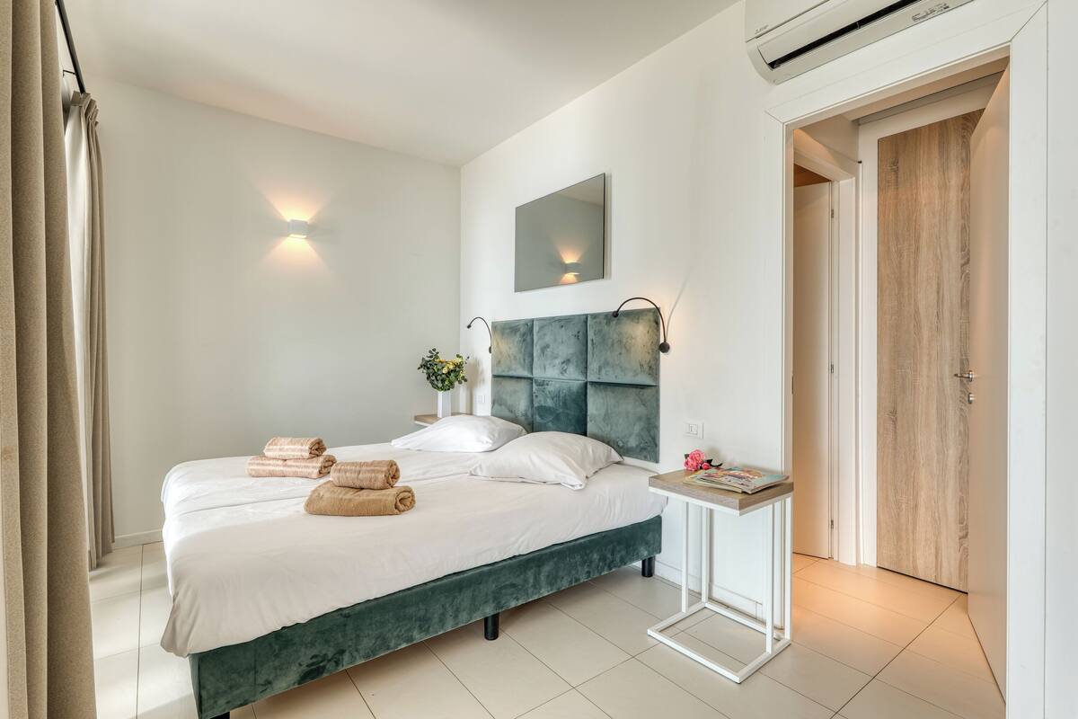 Une chambre moderne avec un grand lit, des tables de chevet, un miroir et une porte en bois.