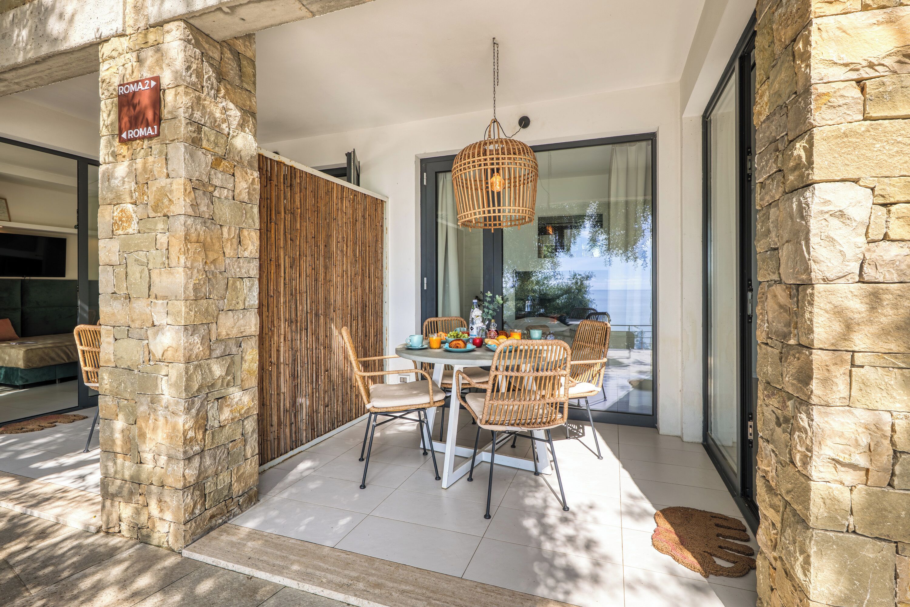 A dining area with stone walls, wicker chairs, and a hanging light fixture.