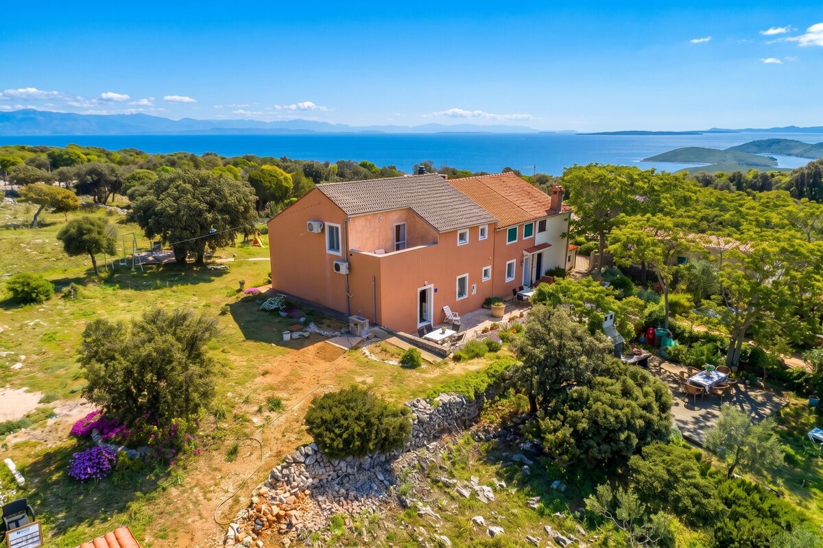 A two-story house with a garden and a view of the sea.