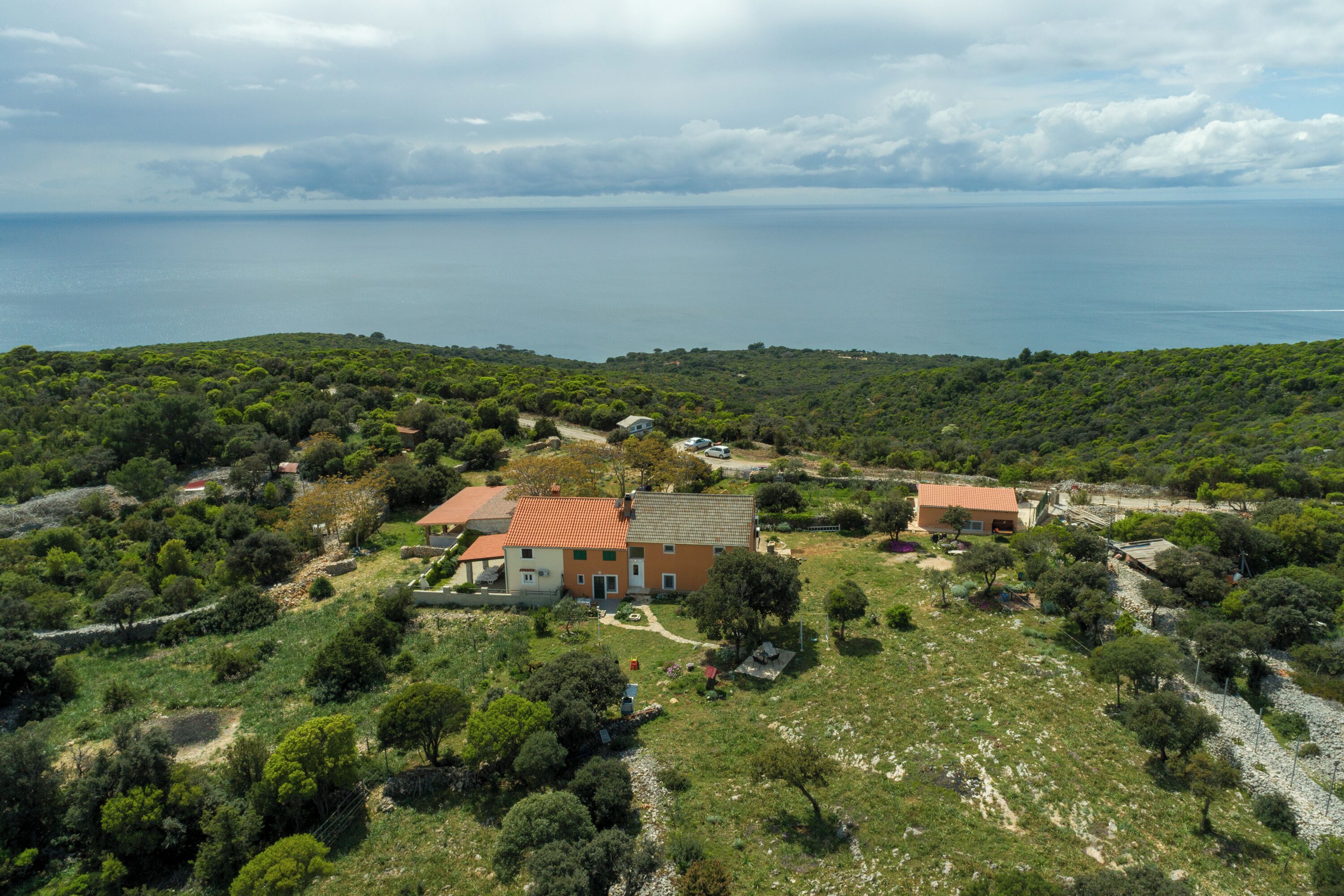 Une propriété située sur la côte, avec une maison entourée d’une végétation luxuriante et offrant une vue sur la mer.