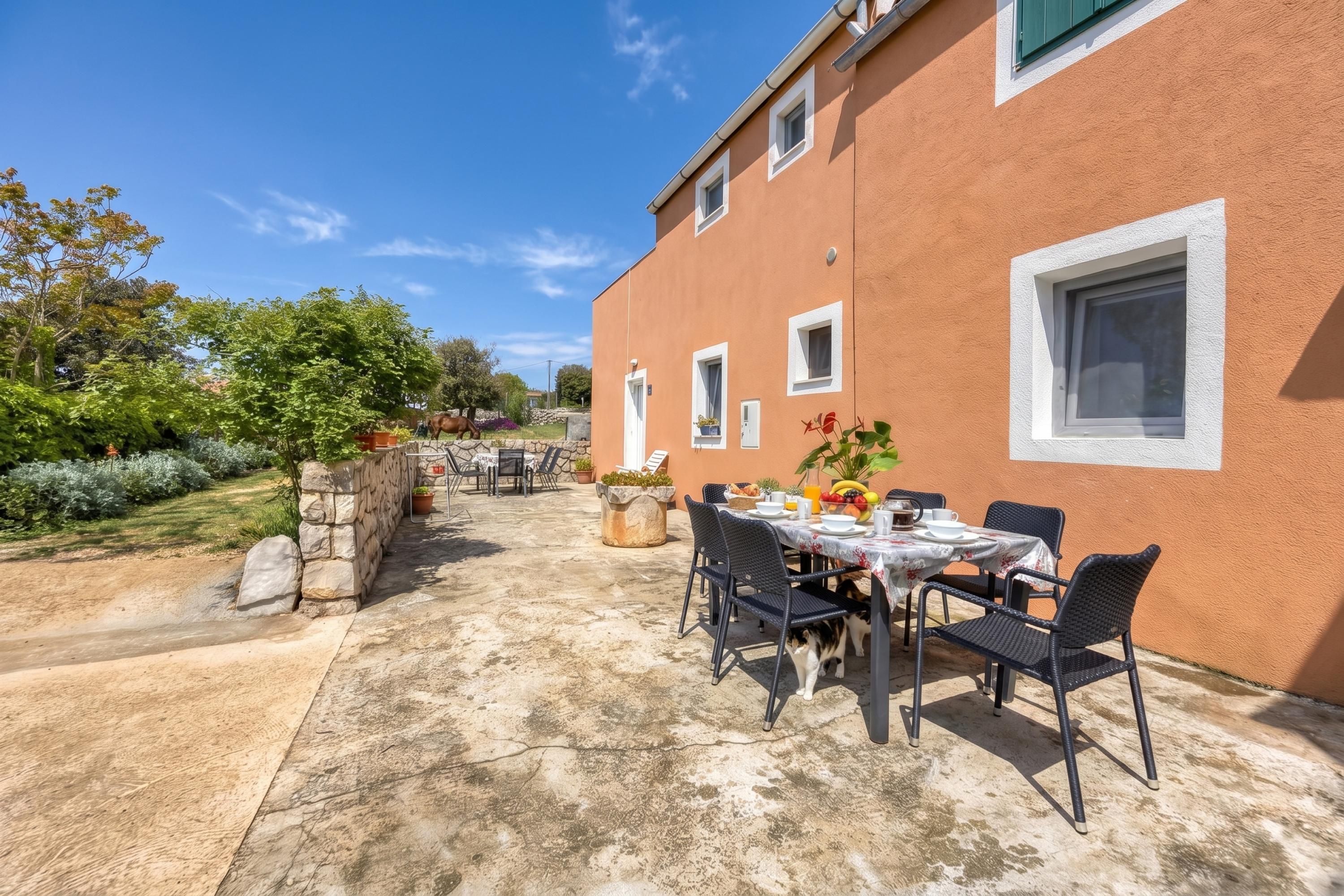 Eine Terrassengruppe mit Esstisch, umgeben von Steinmauern und Topfpflanzen.