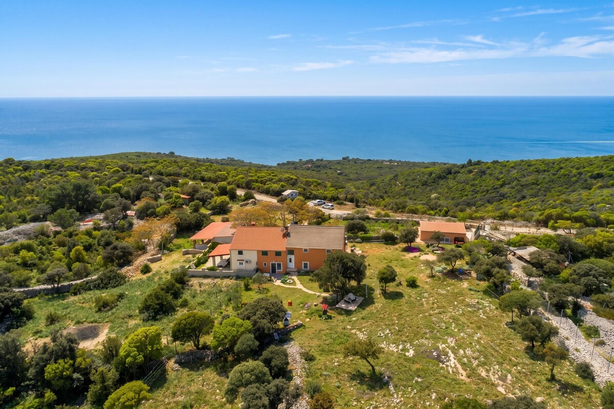 A coastal property with a main building, smaller structures, and a view of the sea.