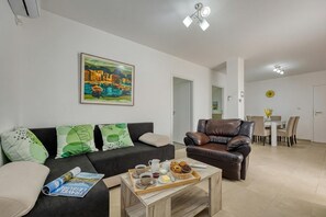 Ein Wohnzimmer mit einer Couch, einem Couchtisch und einem Essbereich mit Tisch und Stühlen.