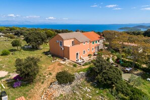 A two-story house with a red-tiled roof, surrounded by a garden and a view of the sea. - Island Top Sea View Estate (Mali Losinj)