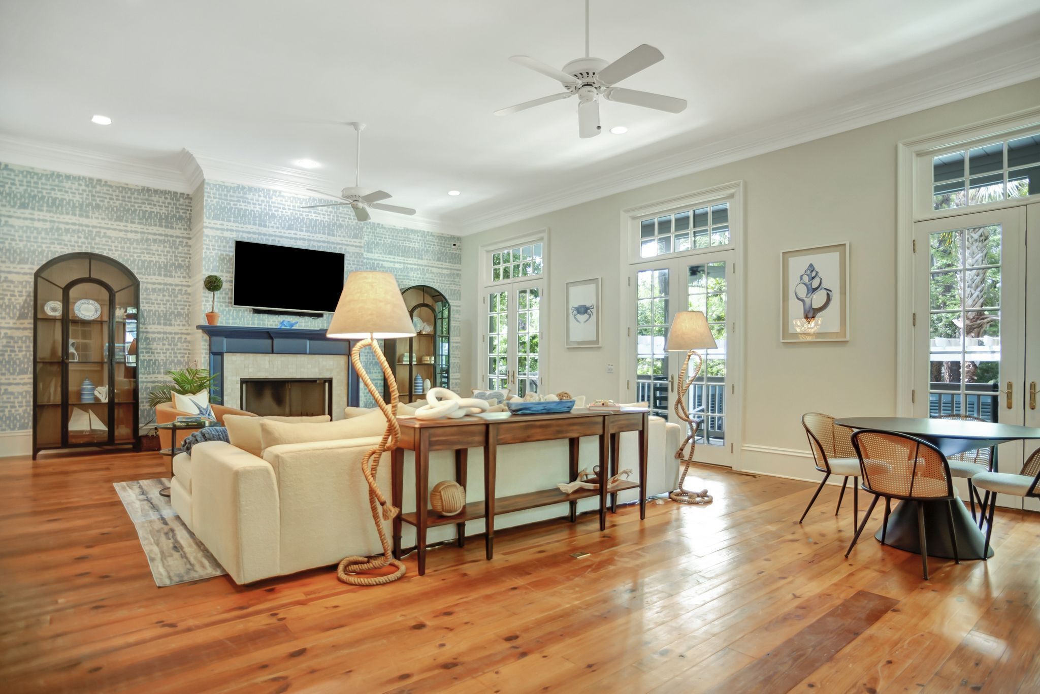 A spacious living room with hardwood flooring, a fireplace, a television, and a dining area with chairs and a table.