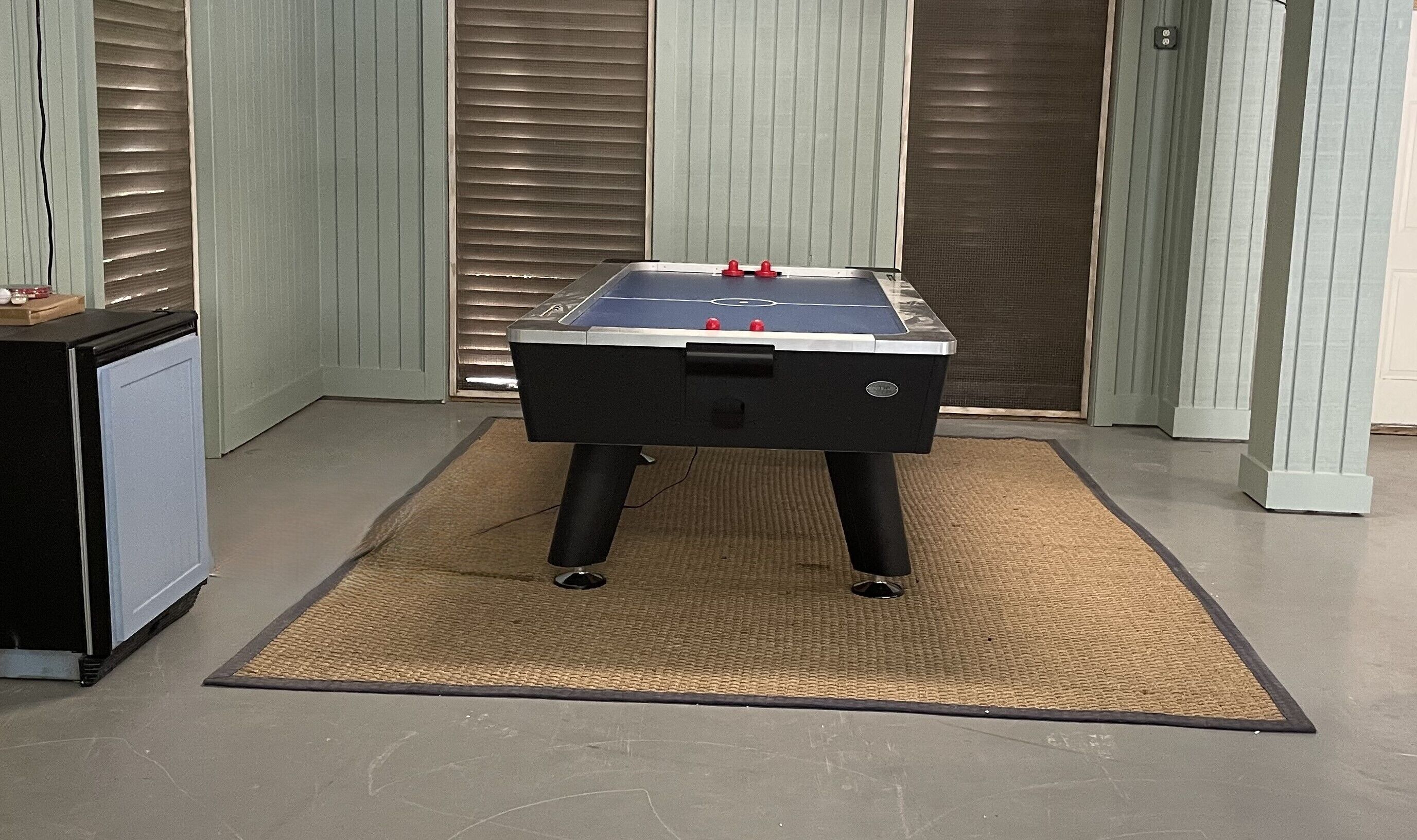 Ein Tischkicker in einem Raum mit einem kleinen Kühlschrank und einer Tür mit einer Sichtschutzvorrichtung.