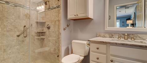 A bathroom with a glass-enclosed shower, a toilet, and a vanity with a mirror.