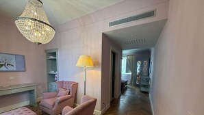 Una stanza con una poltrona rosa, una lampada e un lampadario.