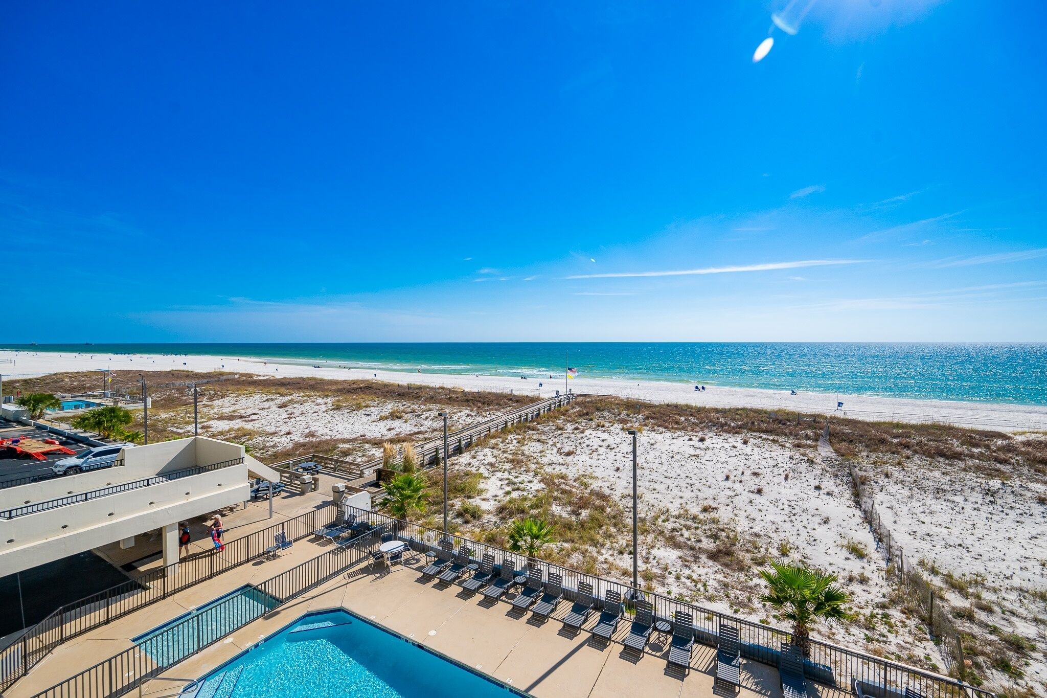A beach view with a pool and lounge chairs.