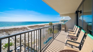 Un balcon avec vue sur la plage et l’océan, équipé d’une table de billard et de chaises longues.