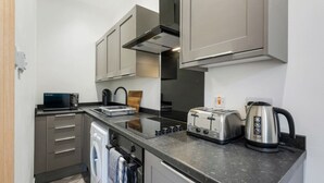 Una cocina compacta con lavadora, tostadora, hervidor y microondas.