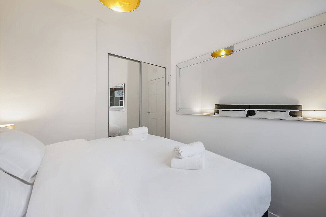 Ein Hotelzimmer mit einem großen Bett, einem Nachttisch, einem Spiegel und einer Wandleuchte.