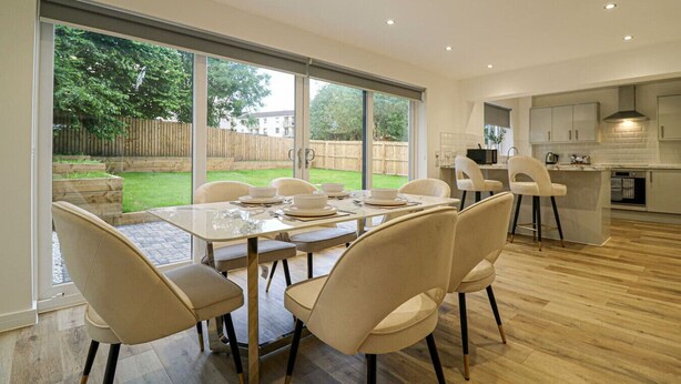 A modern kitchen with a dining area, large windows, and a view of the backyard. - Beautiful 3 Bed Luxury House in Glasgow West End (Glasgow City)