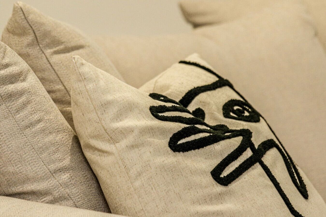 A close-up of a pillow with a black embroidered design.