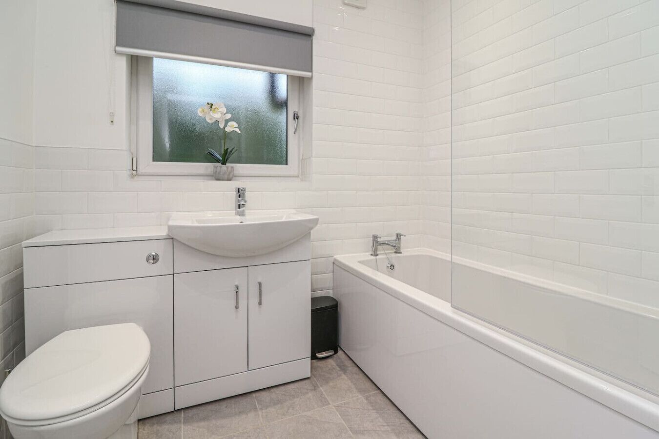 A modern bathroom with a white sink, toilet, and bathtub.