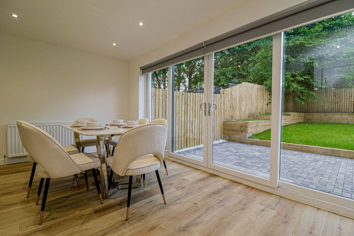 A dining area with a table and chairs, a sliding glass door leading to a garden.