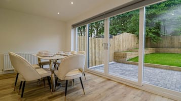 A dining area with a table and chairs, a sliding glass door leading to a garden.