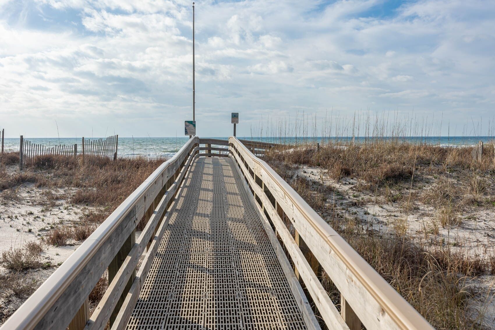 A wooden boardwalk leading to the beach with a clear sky.