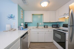 A kitchen with white cabinets, a sink, a toaster, a microwave, a refrigerator, and a dishwasher. - Island Winds West 473 2 Bedroom Condo (Gulf Shores)
