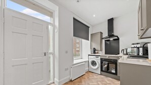 A modern kitchen with a washing machine, oven, and microwave.