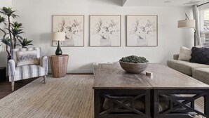 A living room with a wooden coffee table, striped armchair, and a large plant.