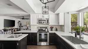 A modern kitchen with a central island, stainless steel appliances, and a ceiling fan.