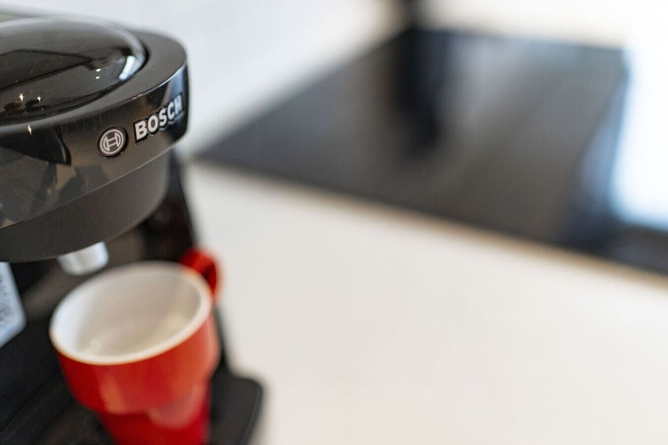 A close-up of a coffee machine with a red cup underneath.
