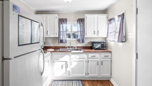 A compact kitchen with white cabinets, a built-in microwave, and a refrigerator.