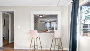 A modern kitchen with white cabinets, a countertop, and two bar stools.