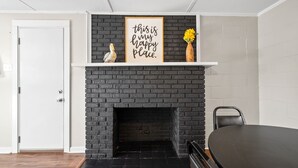 A room with a black brick fireplace, a white door, and a black dining table.