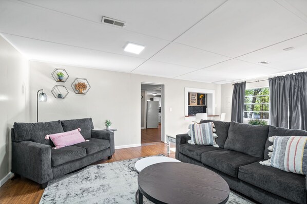 A modern living room with two grey sofas, a round coffee table, and a white rug.