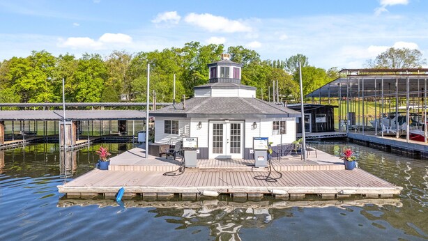 A docked houseboat with a small deck, a covered area, and a water pump.