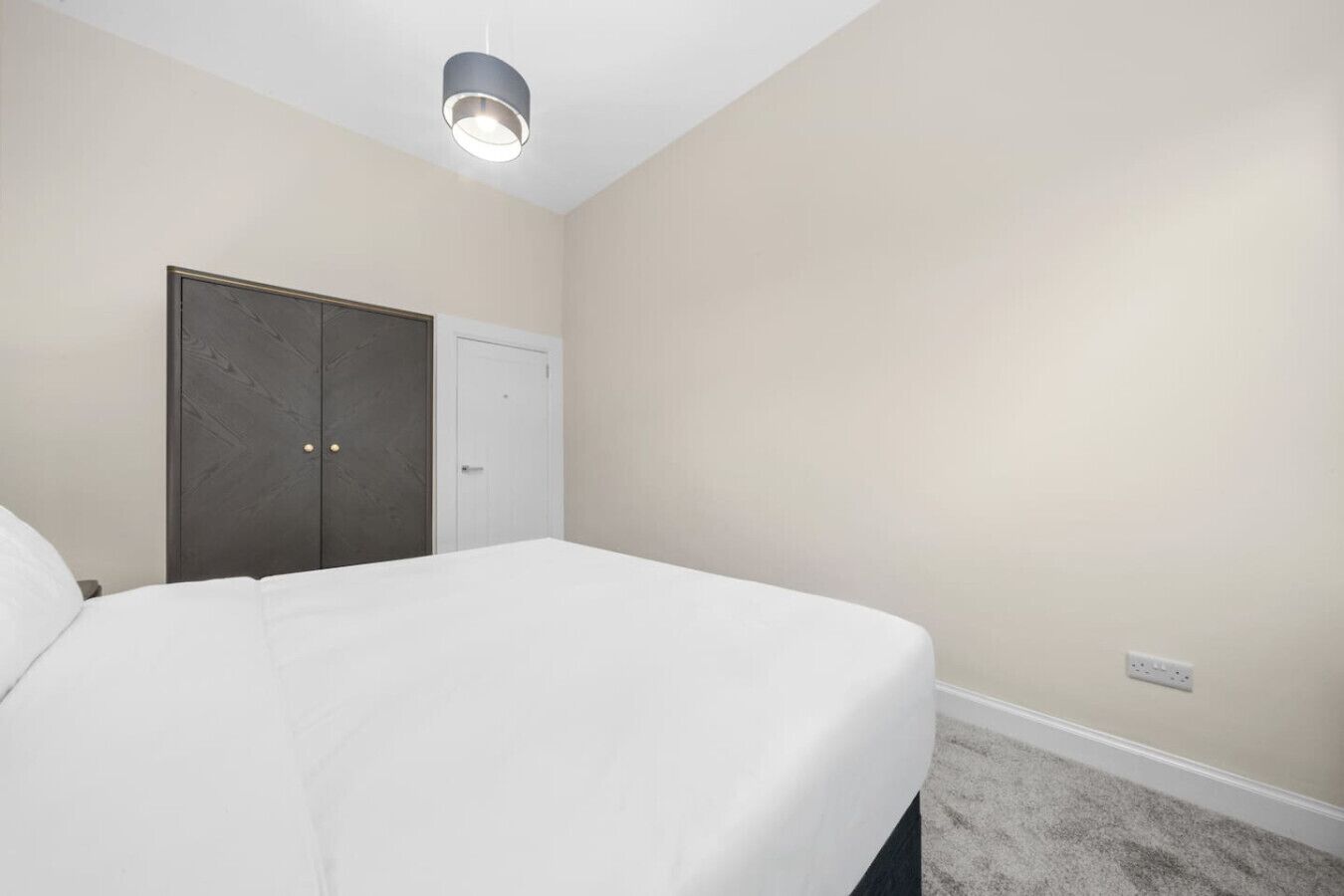 Ein Schlafzimmer mit einem Bett, einem Kleiderschrank, einer Tür und einer Deckenleuchte.