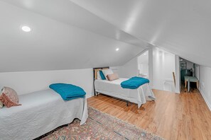 A small, modern room with two beds, a wooden floor, and a ceiling light. - Bungalow Off Floyd St In The Heart Of Covington 3 Bedroom Bungalow (Covington)