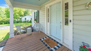A porch with a wooden floor, two wicker chairs, a small table, and a door with a mailbox. - Bungalow Off Floyd St In The Heart Of Covington 3 Bedroom Bungalow (Covington)