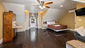 A bedroom with a bed, a ceiling fan, a TV, and a wooden cabinet. - The Sells House 3 Bedroom Home (Galveston)