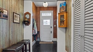 A hallway with wooden walls, a white door, and a wooden cabinet with a sign. - The Sells House 3 Bedroom Home (Galveston)