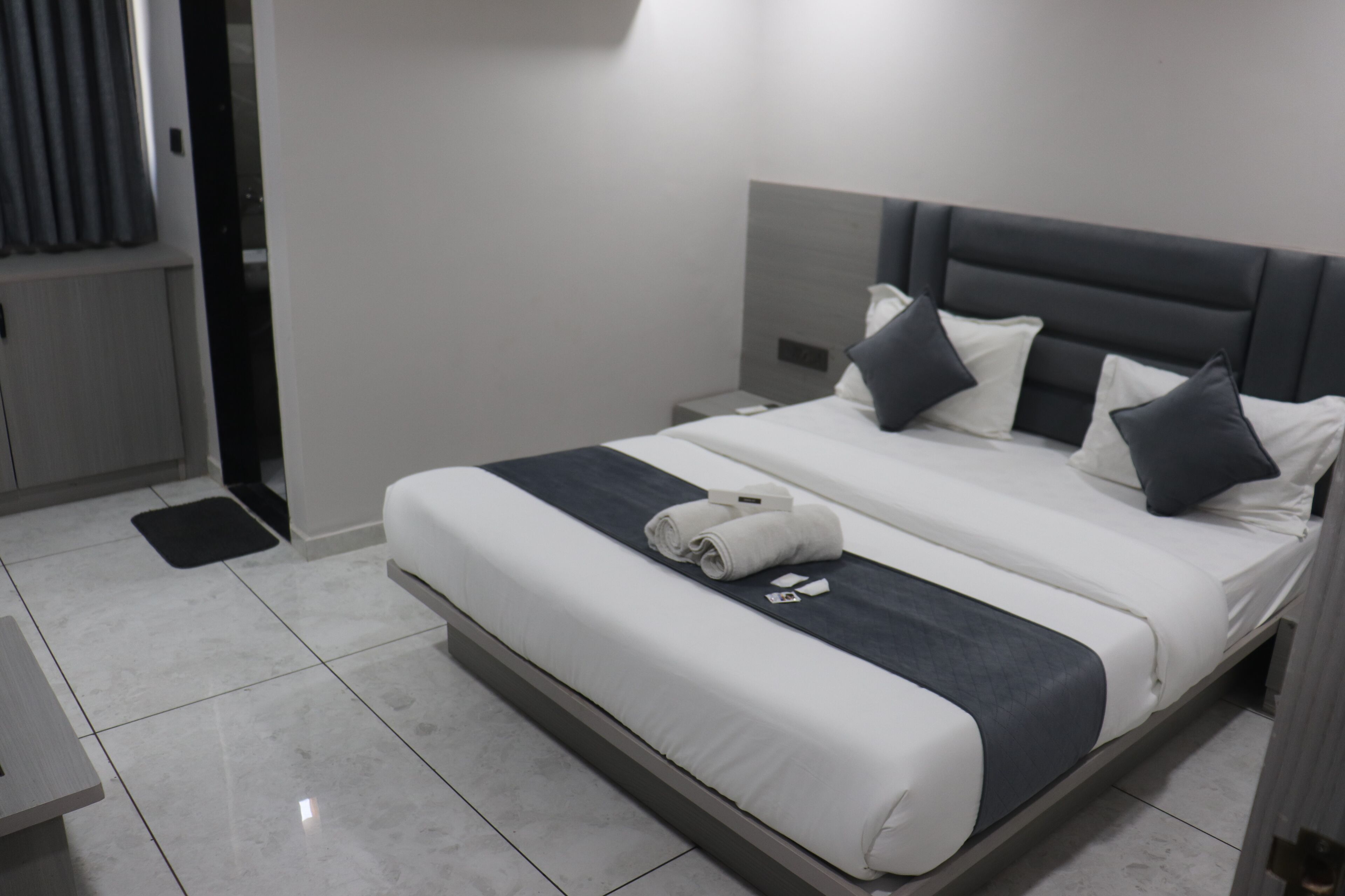 A modern hotel room with a large bed, a bedside table, and a nightstand.