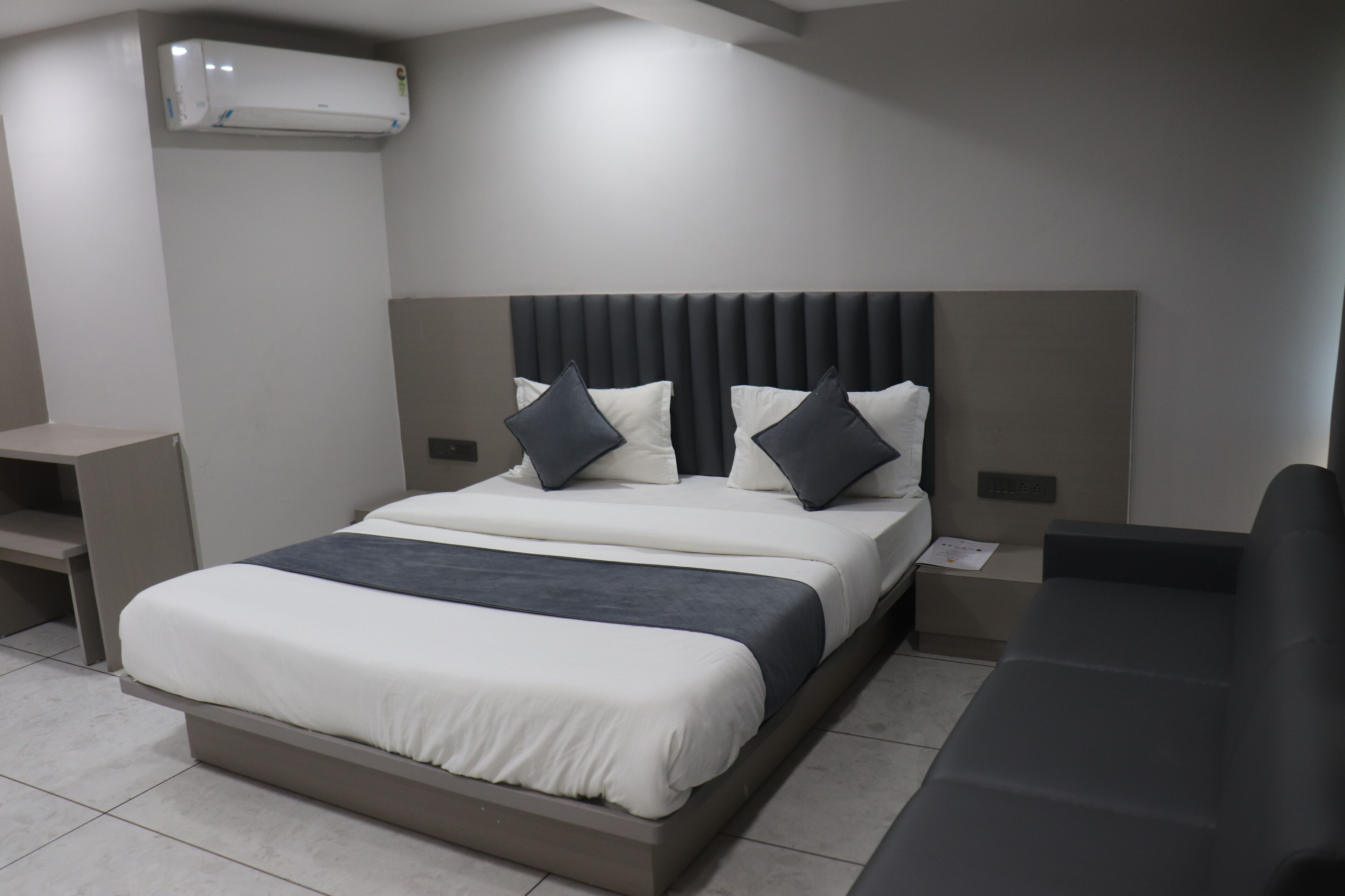 Una habitación de hotel moderna con una cama grande, una mesita de noche y un banco empotrado.